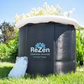 A zenpod portable ice bath standing in a green garden with a bag of ice leaning on it